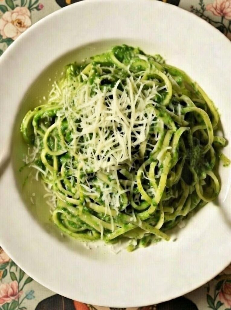 Plato blanco tallarines con salsa verde y queso rallado